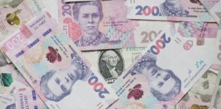 Top view of scattered Ukrainian hryvnia and US dollar banknotes symbolizing wealth.