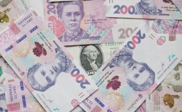 Консерваторы: иностранные инвестиции должны служить канадцам, а не «своим» у либералов Top view of scattered Ukrainian hryvnia and US dollar banknotes symbolizing wealth.
