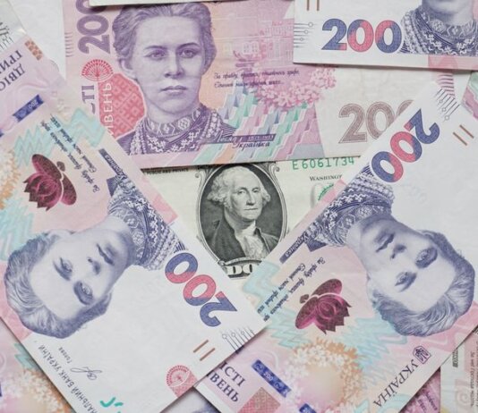 Top view of scattered Ukrainian hryvnia and US dollar banknotes symbolizing wealth.
