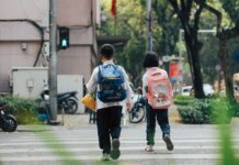 Полиция Гамильтона напоминает о безопасности в начале учебного года Two children with backpacks crossing a street at a pedestrian crossing.