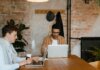 Оттава профинансирует 10 000 стажировок в сфере ИИ для молодых канадцев Two men working on laptops in a stylish office with exposed brick walls.