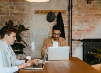 Оттава профинансирует 10 000 стажировок в сфере ИИ для молодых канадцев Two men working on laptops in a stylish office with exposed brick walls.