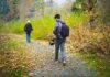 Британская Колумбия вводит код часового пояса PCT — Pacific Time круглый год Two photographers walking down a leaf-covered forest path capturing nature's beauty.