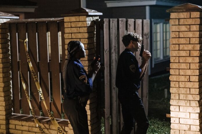 Two police officers investigate a crime scene at night, entering a house with caution. Two police officers investigate a crime scene at night, entering a house with caution.