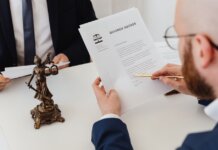 Two professionals examining a divorce decree with a Lady Justice statue nearby.