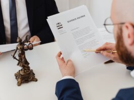 Two professionals examining a divorce decree with a Lady Justice statue nearby.