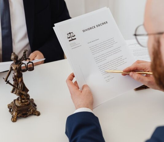 Two professionals examining a divorce decree with a Lady Justice statue nearby.