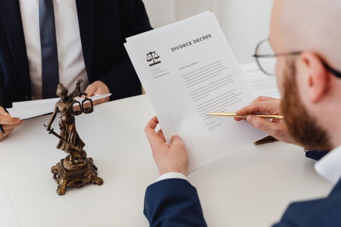 Two professionals examining a divorce decree with a Lady Justice statue nearby. Two professionals examining a divorce decree with a Lady Justice statue nearby.