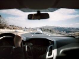 View from a car driving down a scenic highway with hills in the background, depicting a casual road trip.
