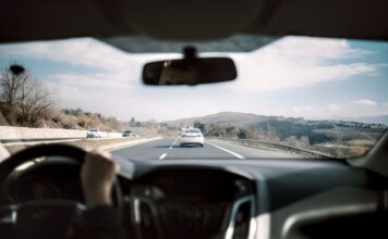 Полиция Калгари ищет записи видеорегистраторов после аварии на Deerfoot Trail View from a car driving down a scenic highway with hills in the background, depicting a casual road trip.