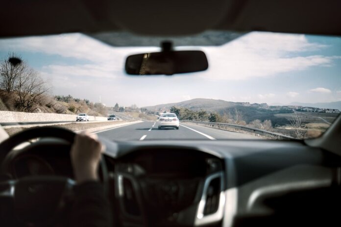 View from a car driving down a scenic highway with hills in the background, depicting a casual road trip. View from a car driving down a scenic highway with hills in the background, depicting a casual road trip.