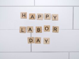 Wooden letter tiles spelling 'Happy Labor Day' on a white tile background.