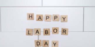 Wooden letter tiles spelling 'Happy Labor Day' on a white tile background.