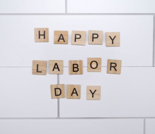 Wooden letter tiles spelling 'Happy Labor Day' on a white tile background.