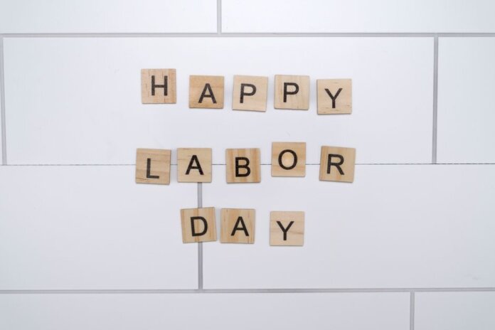 Wooden letter tiles spelling 'Happy Labor Day' on a white tile background.