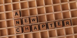 Wooden Scrabble letters arranged to spell 'A New Chapter' on a gridded board.