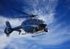 A blue police helicopter patrolling the sky on a clear sunny day.