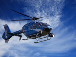 A blue police helicopter patrolling the sky on a clear sunny day.
