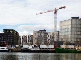 A cityscape featuring modern residential buildings and a construction crane by the waterfront.