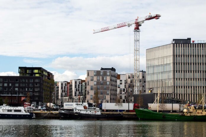 A cityscape featuring modern residential buildings and a construction crane by the waterfront.