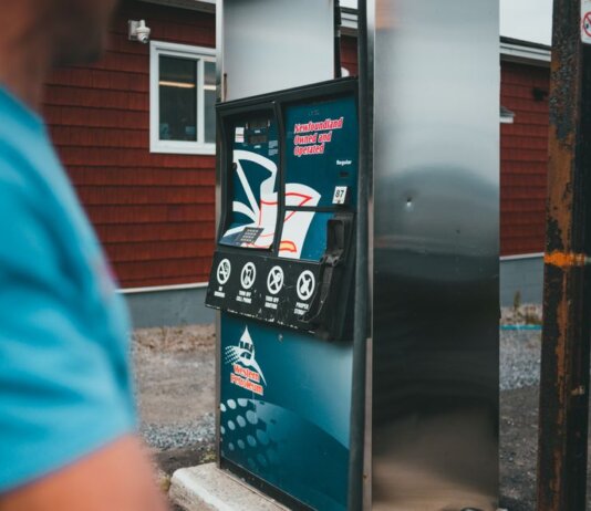 A close-up of a gas pump with a person nearby in Newfoundland, outdoors.