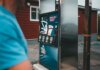 A close-up of a gas pump with a person nearby in Newfoundland, outdoors.