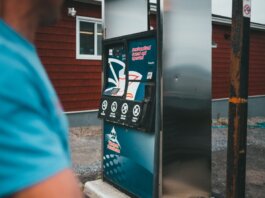 A close-up of a gas pump with a person nearby in Newfoundland, outdoors.