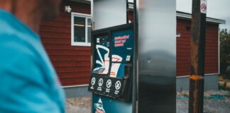 A close-up of a gas pump with a person nearby in Newfoundland, outdoors.