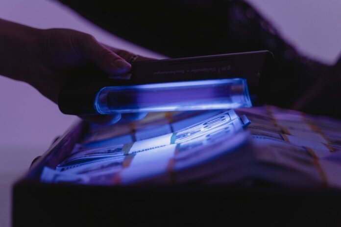A close-up shot of banknotes under UV light to verify currency authenticity and detect counterfeits. A close-up shot of banknotes under UV light to verify currency authenticity and detect counterfeits.