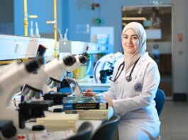 A female scientist in a laboratory setting, conducting research with microscopes and reference books.