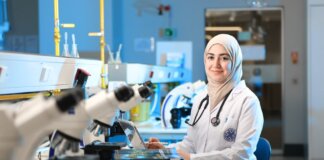 A female scientist in a laboratory setting, conducting research with microscopes and reference books.