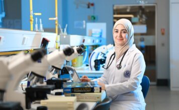 A female scientist in a laboratory setting, conducting research with microscopes and reference books.