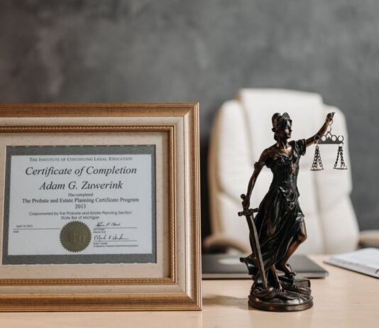 A framed legal certificate and Lady Justice figurine on a desk in a law office setting.