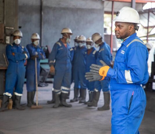 A group of factory workers in safety gear receiving training indoors.