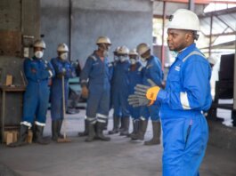 A group of factory workers in safety gear receiving training indoors.