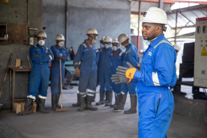 A group of factory workers in safety gear receiving training indoors. A group of factory workers in safety gear receiving training indoors.