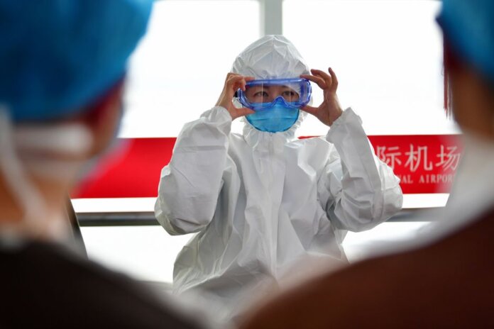 A healthcare professional dons protective clothing at an airport, highlighting safety measures during a pandemic. A healthcare professional dons protective clothing at an airport, highlighting safety measures during a pandemic.