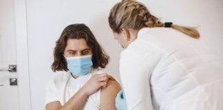 A healthcare worker wearing a mask gives a vaccine shot to a patient in a medical office.