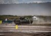 Пожар на военной базе Уэйнрайт в Альберте вышел за пределы учебного полигона A military tank firing a shell during training in an open field.