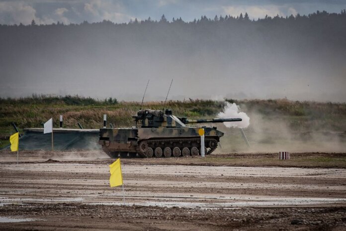 A military tank firing a shell during training in an open field. A military tank firing a shell during training in an open field.