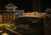 В Калгари двоим предъявили обвинения в похищении женщины, третьего подозреваемого ищут A parked police car at night in front of suburban houses with lights on, creating a dramatic mood.