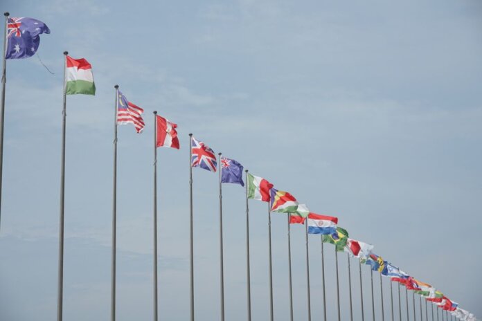 A row of international flags on flagpoles symbolizing global unity and diplomacy. A row of international flags on flagpoles symbolizing global unity and diplomacy.