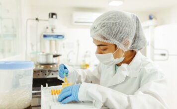 A scientist wearing protective gear performs a meticulous experiment in a laboratory setting.
