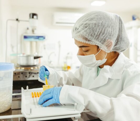 A scientist wearing protective gear performs a meticulous experiment in a laboratory setting.