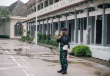 Консерваторы раскритиковали контракт CRA с американской охранной фирмой Allied Universal A security guard stands alert with a megaphone outside a building after rain.