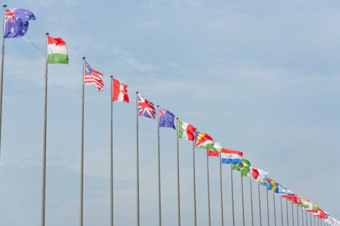 A series of international flags flying in a line against a clear blue sky, symbolizing global unity. A series of international flags flying in a line against a clear blue sky, symbolizing global unity.