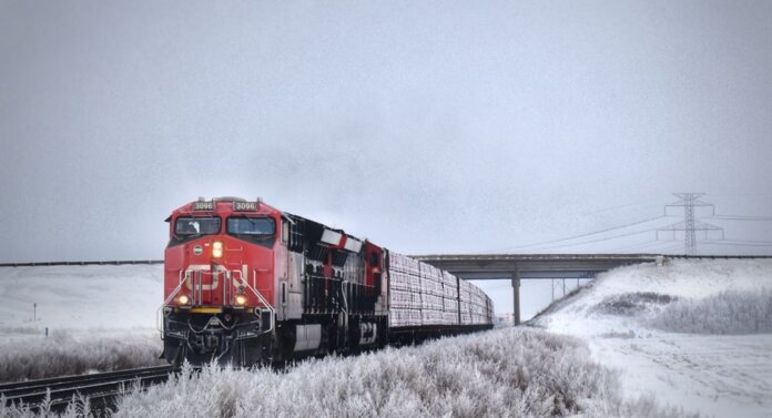 A striking red freight train travels through snowy Grasswood, Saskatchewan, on a winter day. A striking red freight train travels through snowy Grasswood, Saskatchewan, on a winter day.