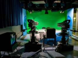 A TV studio setup featuring cameras and a green screen for production purposes.