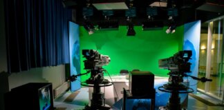 A TV studio setup featuring cameras and a green screen for production purposes.