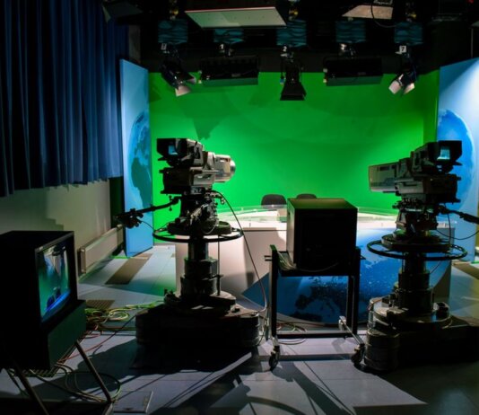 A TV studio setup featuring cameras and a green screen for production purposes.